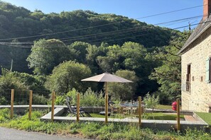 A patio with outdoor furniture, a table set for dining, and a stone building in the background. - Comfortable and authentic holiday home in Orgnac-sur-Vézère on the Vézère (Orgnac-sur-Vézère)