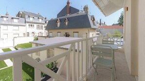 A balcony with a metal railing and a table with chairs, overlooking a residential area with houses. - 1BDR/3P flat - balcony - in the heart of Deauville (Deauville)
