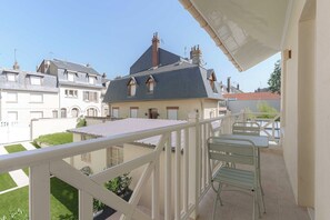 A balcony with a metal railing and a table with chairs, overlooking a residential area with houses. - 1BDR/3P flat - balcony - in the heart of Deauville (Deauville)