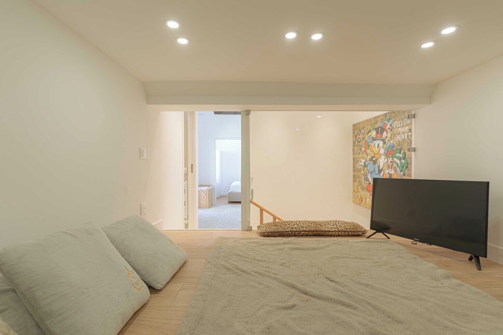 A modern living room with a sofa, a television, and a large rug.