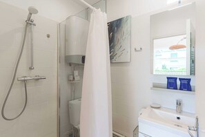 A bathroom with a shower, toilet, sink, and a window with a view. - Flat in a traditional Norman townhouse – Garden (Deauville)