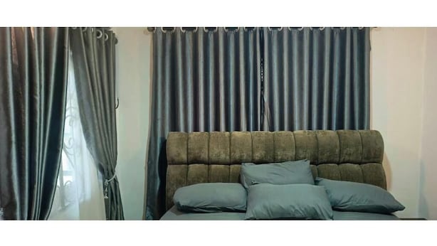 Cama com cabeceira, cortinas e almofadas.