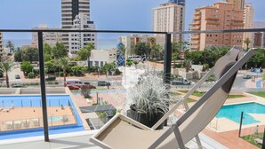 A balcony with a lounge chair, a pool, and a view of the cityscape. - CostaBlancaDreams - Arenal Beach 10 in Calpe (Calpe / Calp)