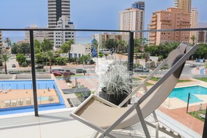Uma varanda com espreguiçadeira, piscina e vista para a paisagem urbana.