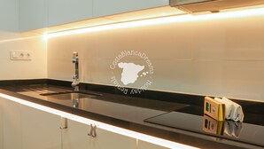 A modern kitchen with a black countertop, a stainless steel sink, and a logo on the backsplash. - CostaBlancaDreams - Arenal Beach 10 in Calpe (Calpe / Calp)