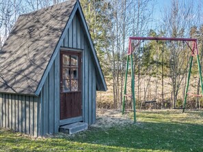 A small wooden cabin with a dark brown door and a sloped roof.