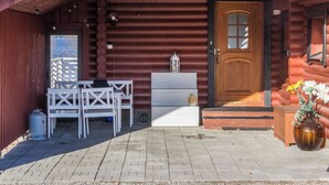 Puuinen mökki, jossa on etuovi, penkki ja pöytä ulkona.