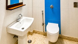 Ein Badezimmer mit einem weißen Waschbecken, einer Toilette und einer blauen Duschwand.
