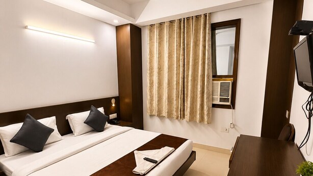 Ein Hotelzimmer mit Bett, Schreibtisch, Deckenventilator und einem Vorhangfenster.