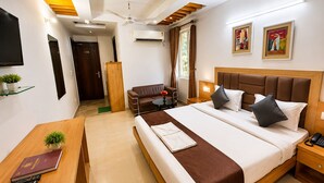 Ein Hotelzimmer mit Bett, Nachttisch, Schreibtisch, Stuhl und Fernseher an der Wand.