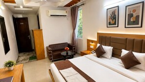 Ein modernes Hotelzimmer mit einem großen Bett, einem Schreibtisch, einer Couch und einem Deckenventilator.