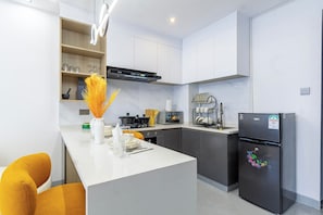 A modern kitchen with a central island, built-in appliances, and a dining area with yellow chairs. - Modern Luxury Apartment | Sauna, Pool, Gym & Balcony (Nairobi)