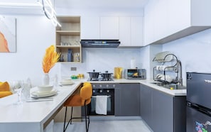 Une cuisine compacte dotée d’un îlot central, d’un four encastré, d’un micro-ondes et d’un réfrigérateur noir.