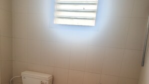 A small bathroom with a toilet, a bidet, and a red bucket. - VIP Residency (Tirupati)
