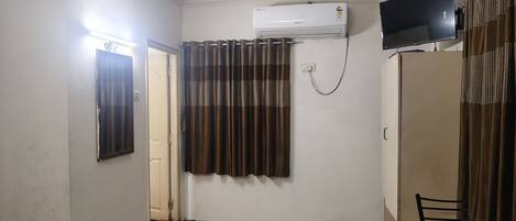 A room with a ceiling fan, an air conditioning unit, a television, and a chair.