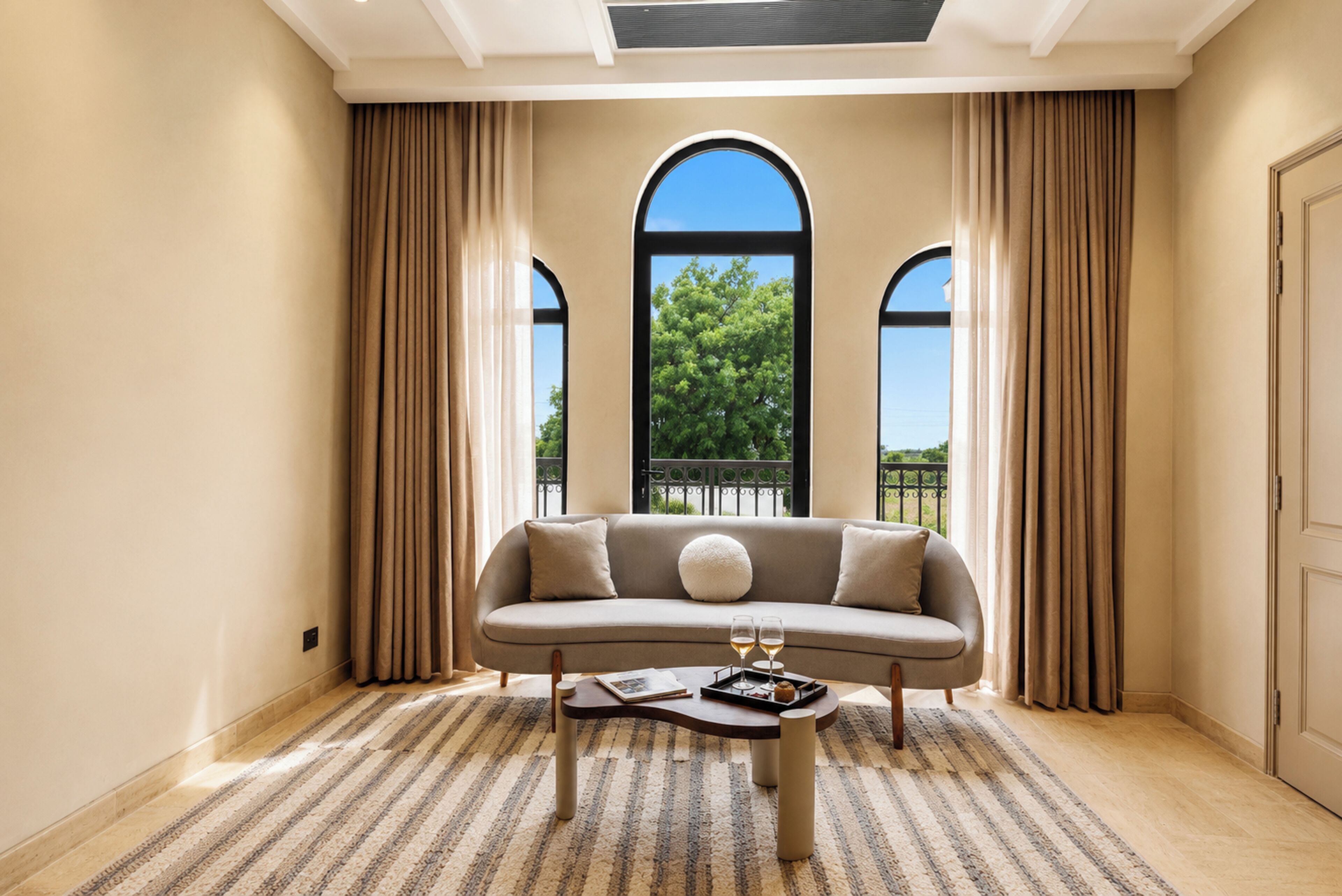 A room with a sofa, a coffee table, and a view through large windows.