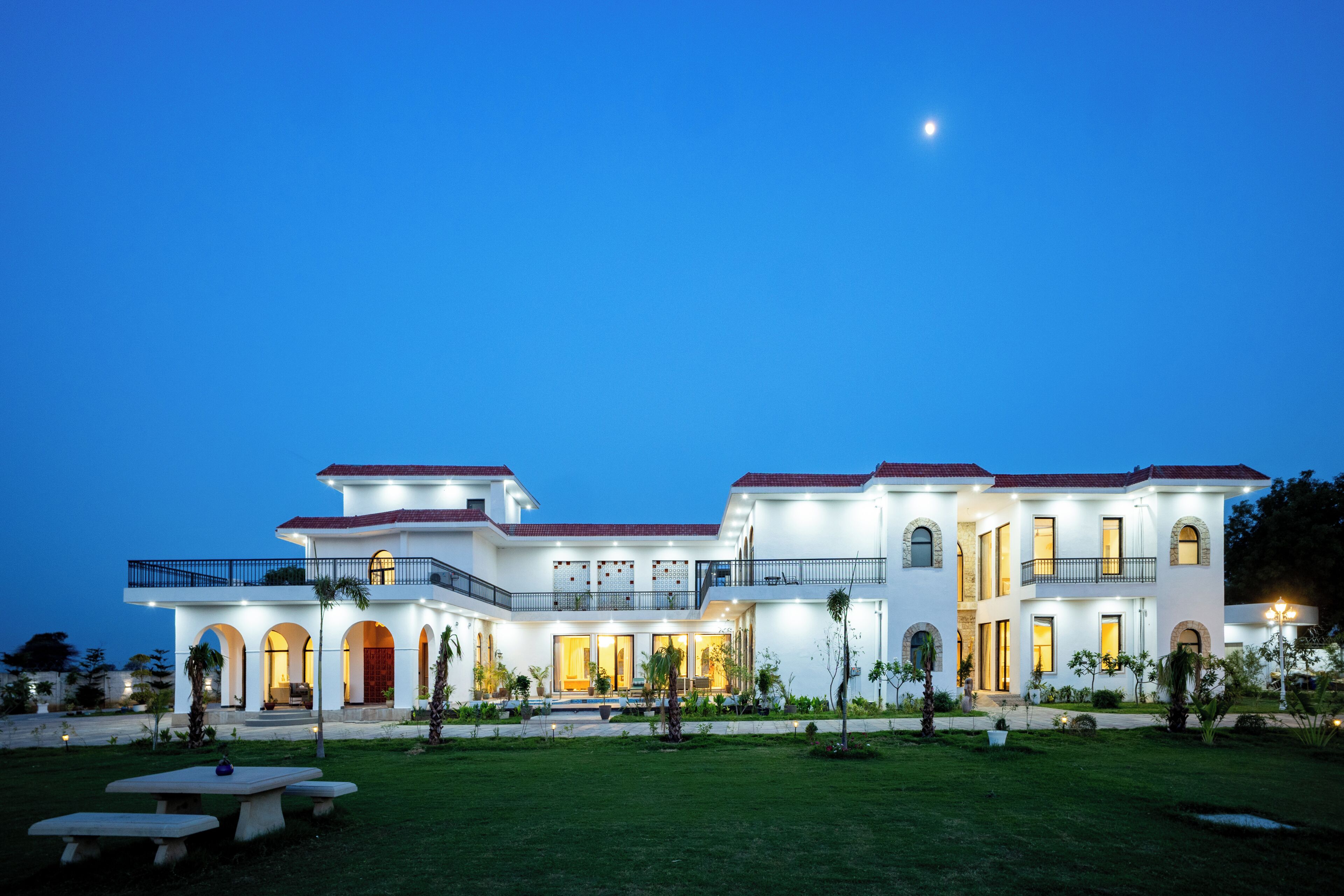 A large, multi-story building with a symmetrical facade, multiple balconies, and a well-maintained lawn.