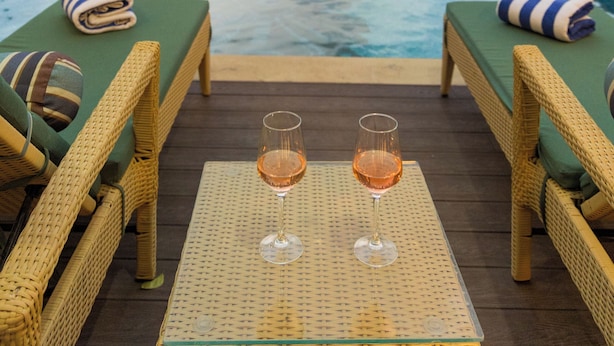 Een zwembadterras met ligbedden en een tafel, met uitzicht op een zwembad.