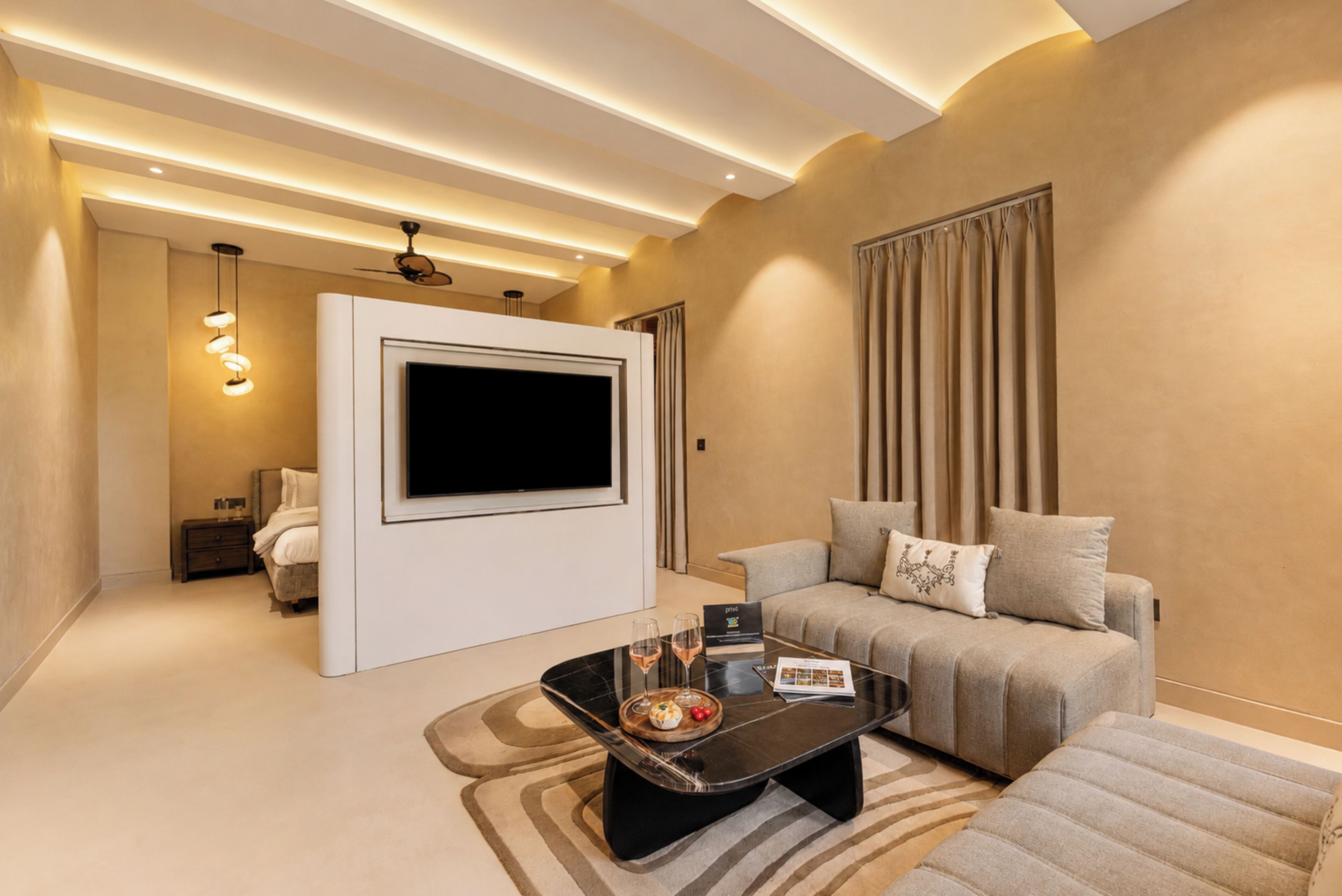 Una sala de estar moderna con televisor de pantalla plana, un sofá, una mesa de centro con una bandeja de bocadillos y un ventilador de techo.
