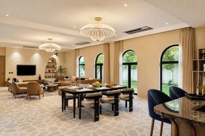 A spacious living area with a dining table, sofas, and a television. - ELIVAAS Prive Heaven 6BHK Villa wth Pool (Sohna)