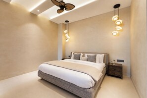 A modern bedroom with a large bed, a ceiling fan, and pendant lighting. - ELIVAAS Prive Heaven 6BHK Villa wth Pool (Sohna)