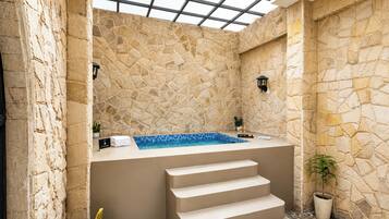 A stone-walled spa area with a hot tub, a small pool, and a set of stairs leading to a higher level.
