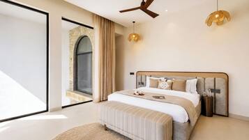 Un dormitorio moderno con una cama grande, un ventilador de techo y vistas a un arco de piedra.