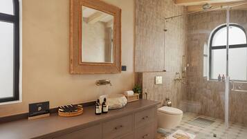 A bathroom with a vanity, a mirror, a shower, and a toilet.