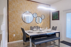 A dining area with a table set for four, a wall-mounted mirror, and a door with a window. - Book Your Christmas Stay/Your Holiday Gift Awaits! (Davenport)