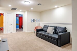 A living room with a black leather sofa, a pink chair, and a small table with a remote control. - Book Your Christmas Stay/Your Holiday Gift Awaits! (Davenport)
