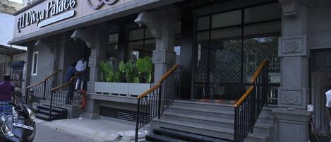 Um edifício com uma placa que diz 'Divya Palace' e uma escadaria que leva à entrada.