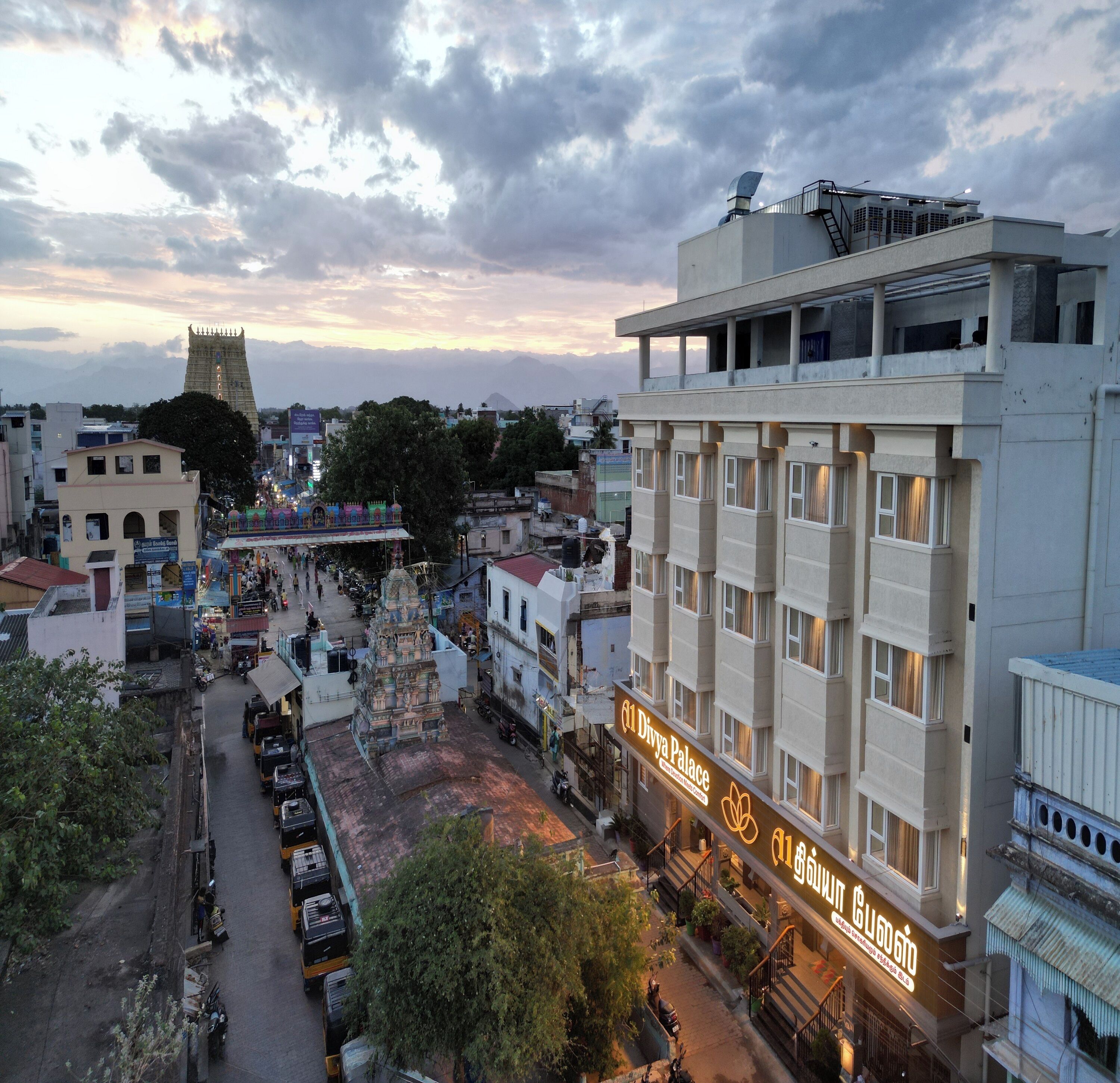 A hotel with a sign indicating it is a Divya Palace, featuring a modern architectural style with multiple floors and balconies.