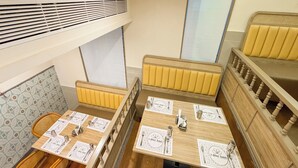 Un comedor con mesas y bancos de madera, equipado con cubiertos y servilletas.