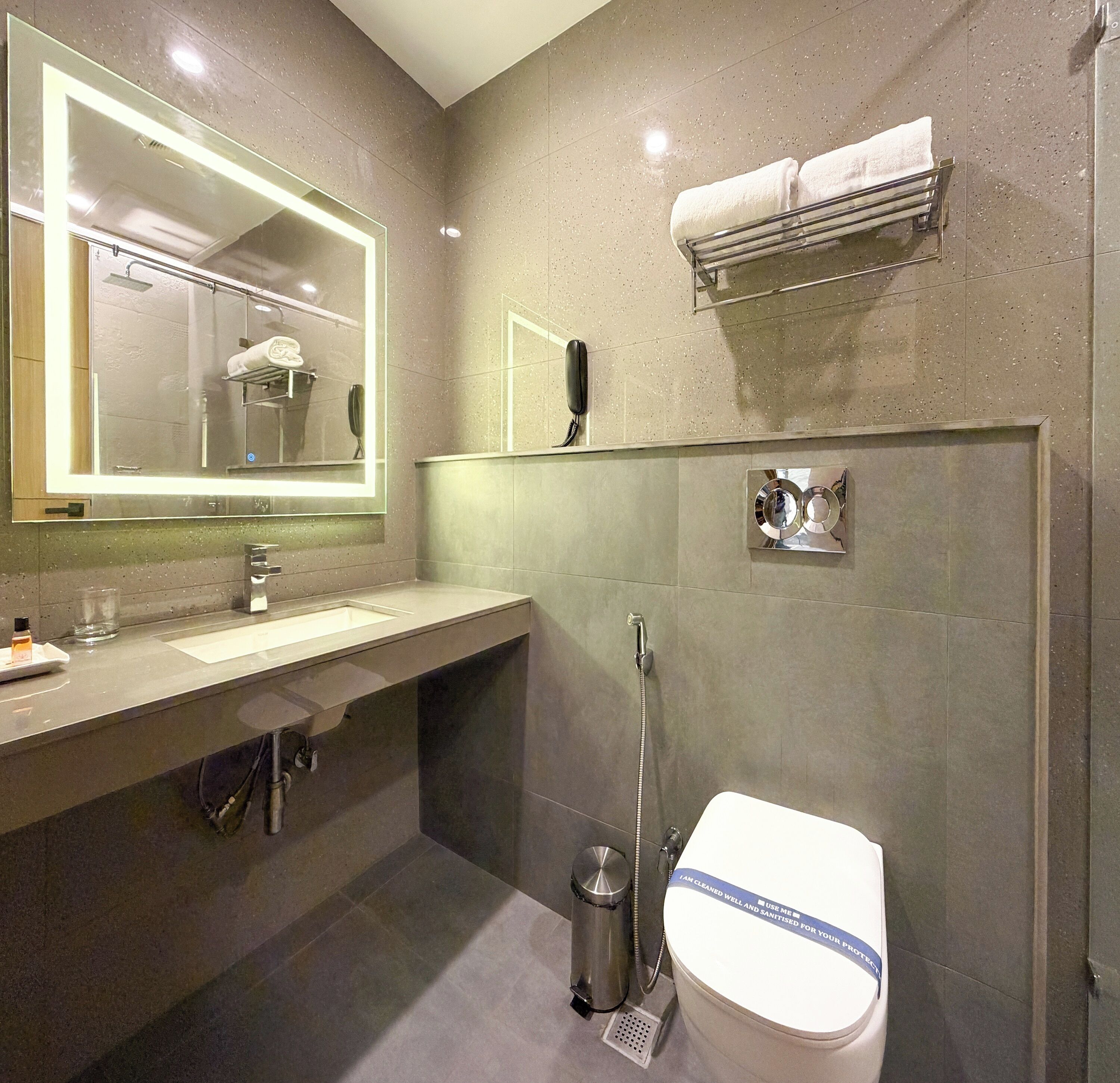 A modern bathroom with a large mirror, a sink, a toilet, and a shower.