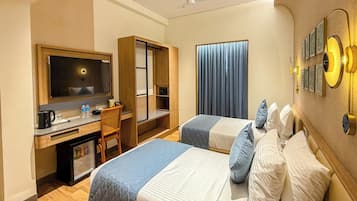 Habitación de hotel con cama, escritorio, silla, televisor y ventilador de techo.