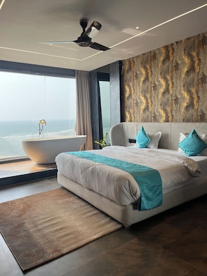Un dormitorio moderno con una cama grande, una bañera y vistas al océano.