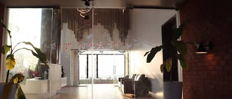 Un interior moderno con un separador de vidrio, una recepción y un área de estar con vistas al exterior.