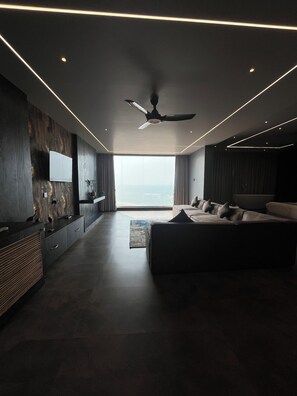 Un dormitorio moderno con una cama grande, un ventilador de techo y vista al océano.