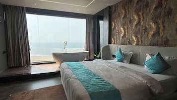 Une chambre moderne avec un grand lit, un ventilateur de plafond et une vue sur l’océan.