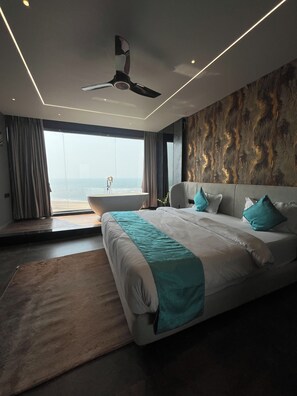 A modern bedroom with a large bed, a ceiling fan, and a view of the ocean. - Sea Horizon Luxury Resort  (Vengurla)
