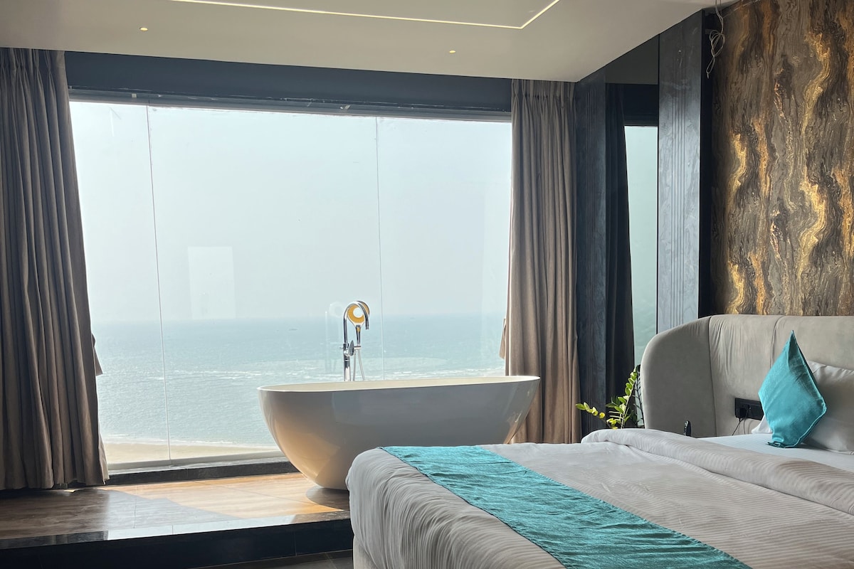 Un dormitorio moderno con una cama grande, una bañera y vista al océano.