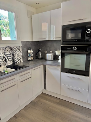 Une cuisine moderne avec des meubles blancs, un four à micro-ondes, un four et un grille-pain encastrés.