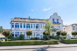Um hotel com vários andares, varandas, área de estar coberta ao ar livre e paisagismo bem cuidado.