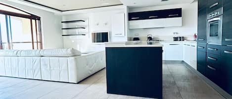 A modern kitchen with a central island, built-in appliances, and a large window.