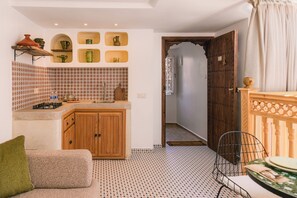 A compact kitchen with a tiled backsplash, wooden cabinets, and a built-in shelf with decorative items. - Your Douiria (Marrakech)