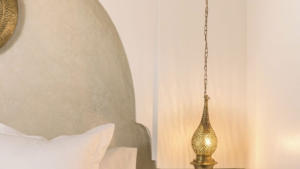 A bed with white bedding, a hanging lamp with a chain, and a wooden chest of drawers. - Your Douiria (Marrakech)