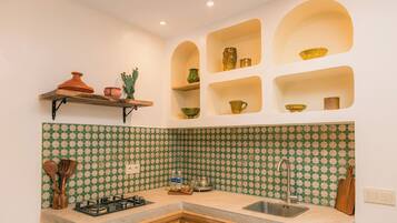 Cozinha com fogão a gás, pia e painel de parede com padrão verde e bege.