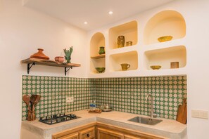 A kitchen with a gas stove, a sink, and a backsplash with a green and beige pattern. - Your Douiria (Marrakech)