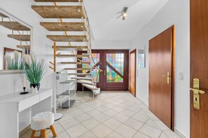 Ein modernes Interieur mit einer Holztreppe, einem weißen Empfangsschalter und einer Holztür.