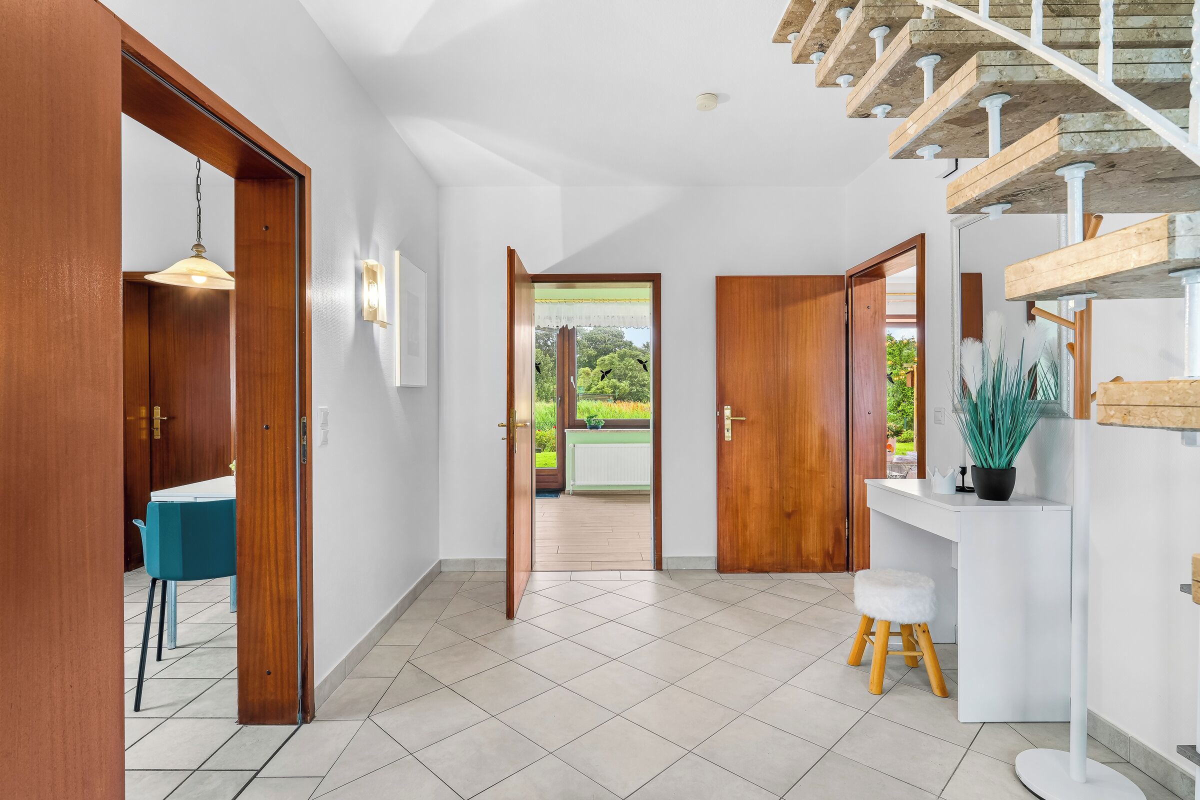 A modern interior with a staircase, a dining area, and a view to the outside.